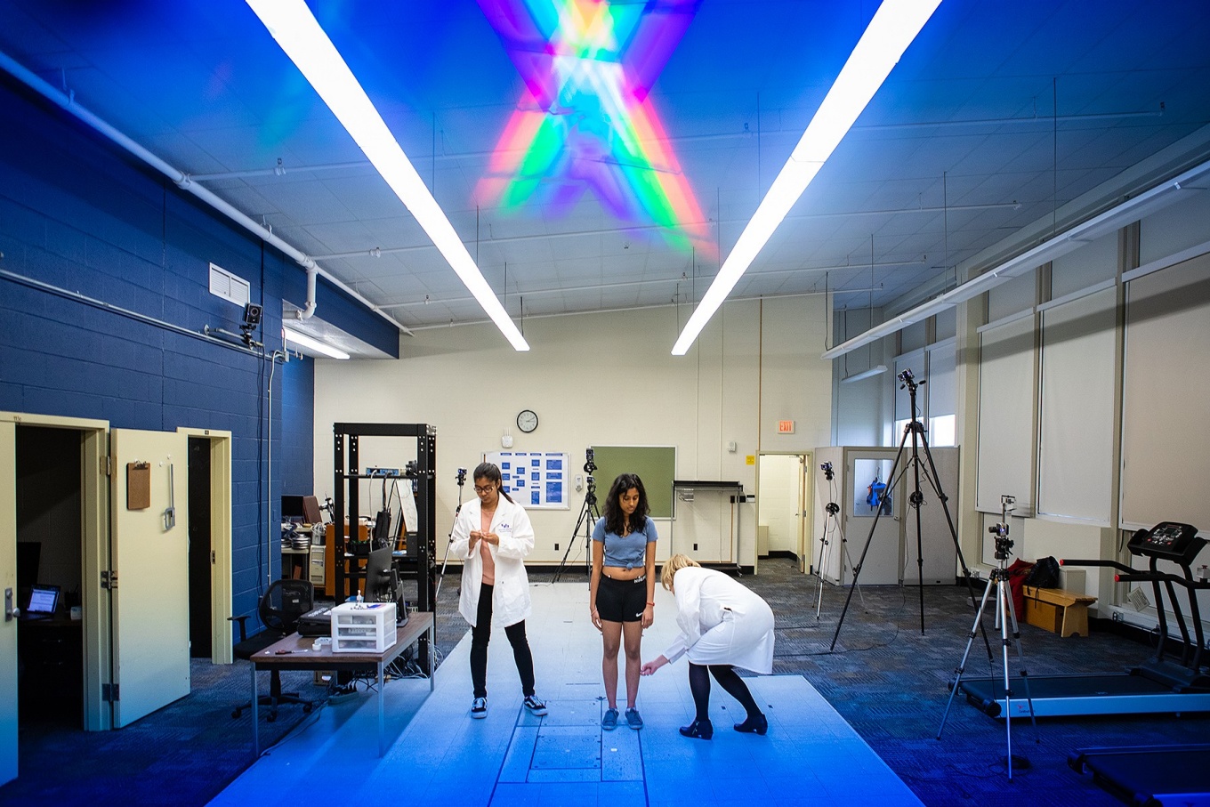 Two people in lab coats work with a patient in a rehabilitation lab.