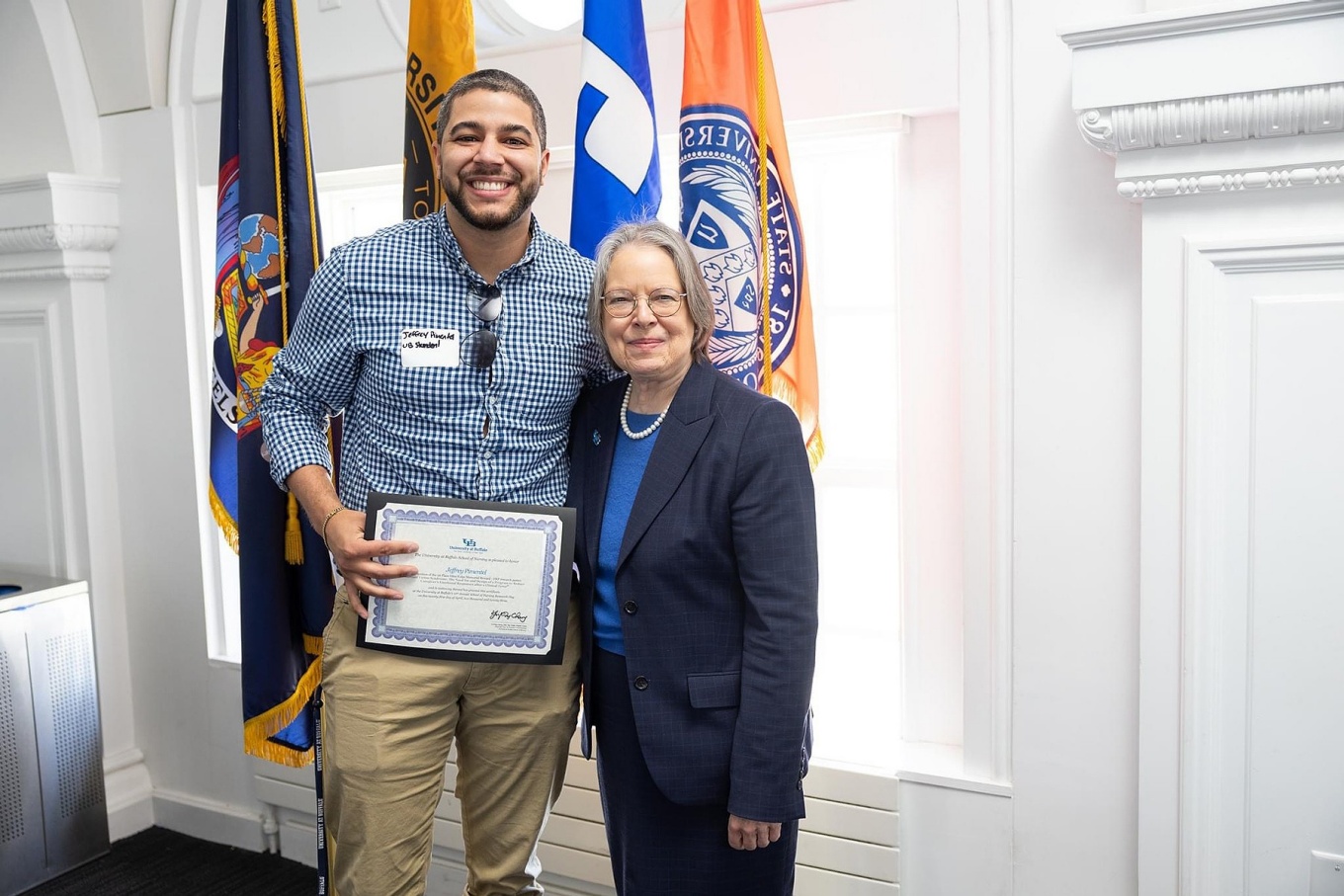 Jeff Pimentel holds a certificate and poses with Nursing School dean Annette Wysocki. 