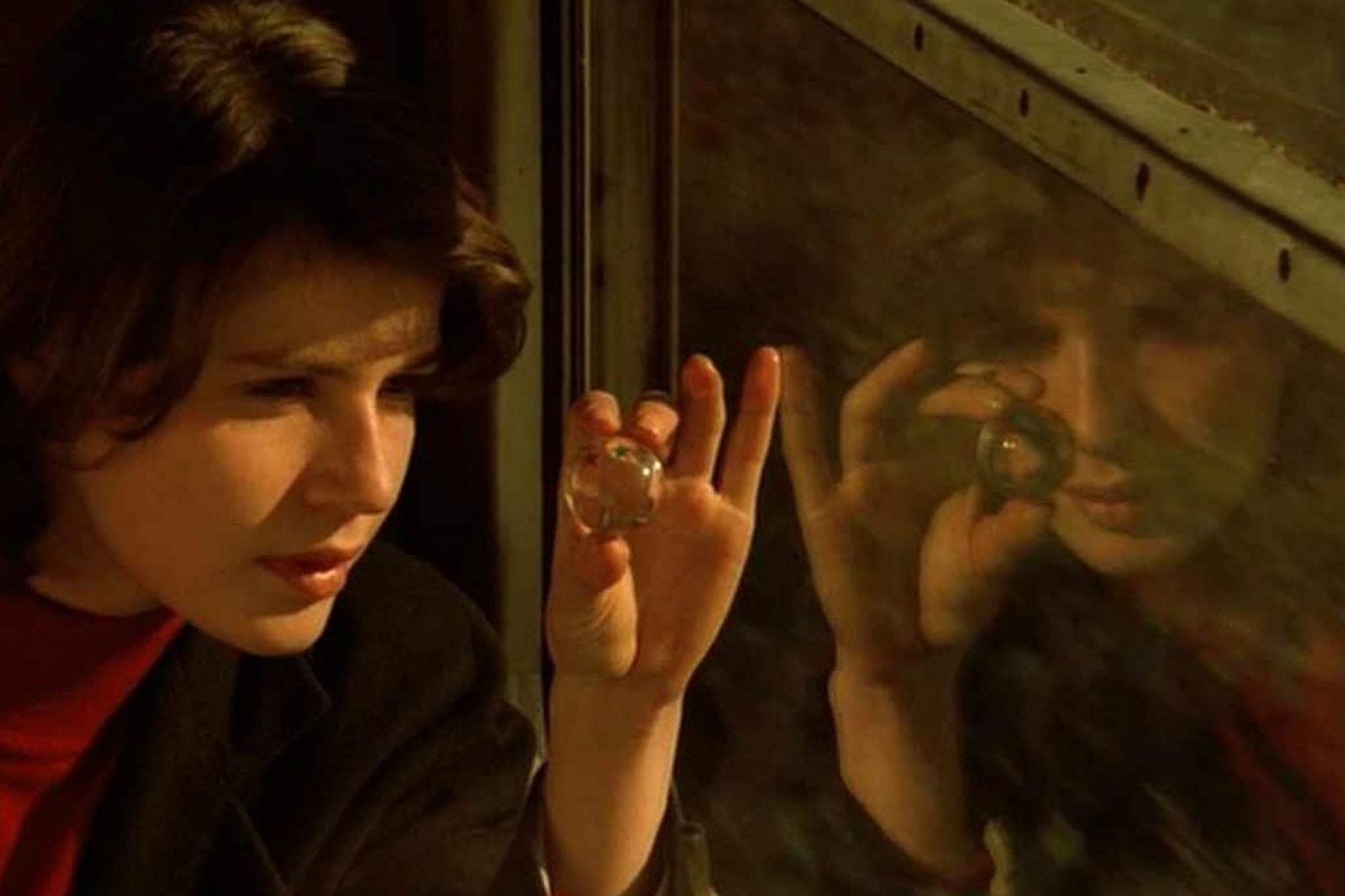 Scene from “The Double Life of Véronique,” of a woman looking through a small glass globe at a window. 