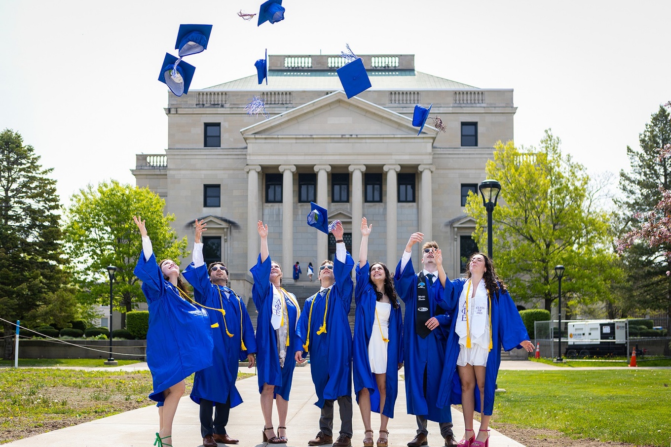 Graduates tossing caps, Abbott Hall in the background. 