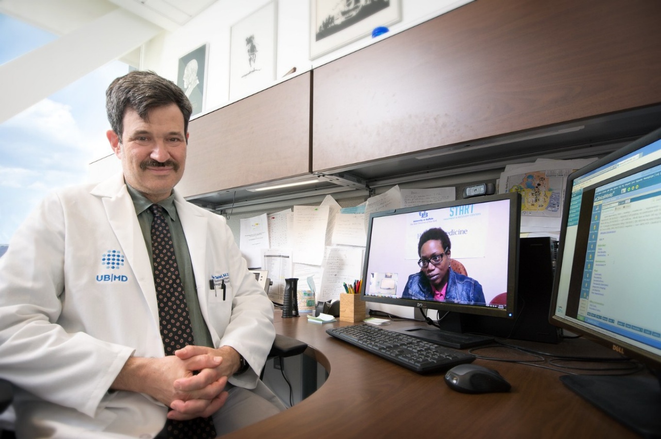 Andrew Talal sits at a desk with a laptop open to a telehealth session. 