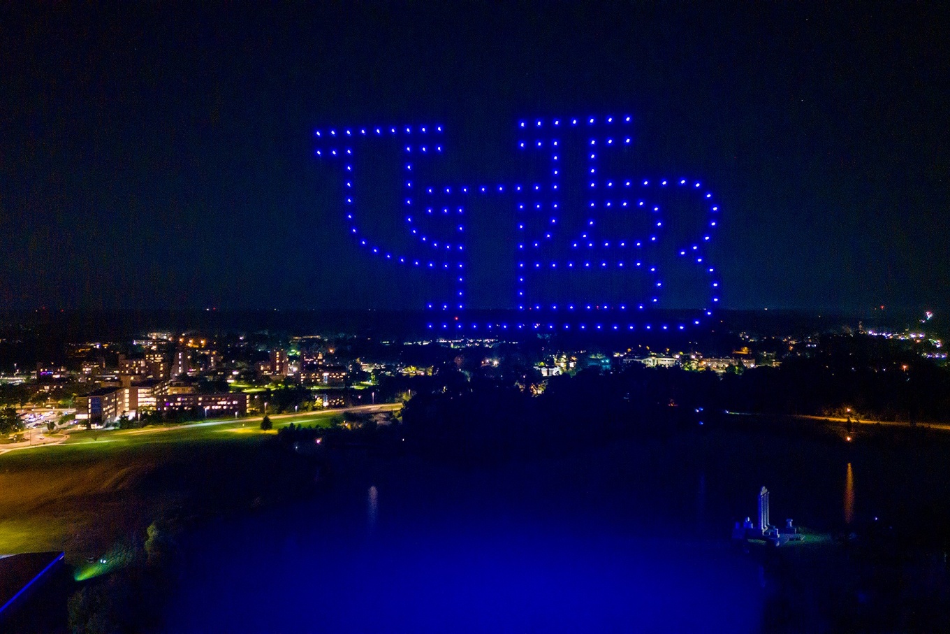 Drones form the interlocking UB in lights over Lake LaSalle during a Welcome Weekend drone light show.