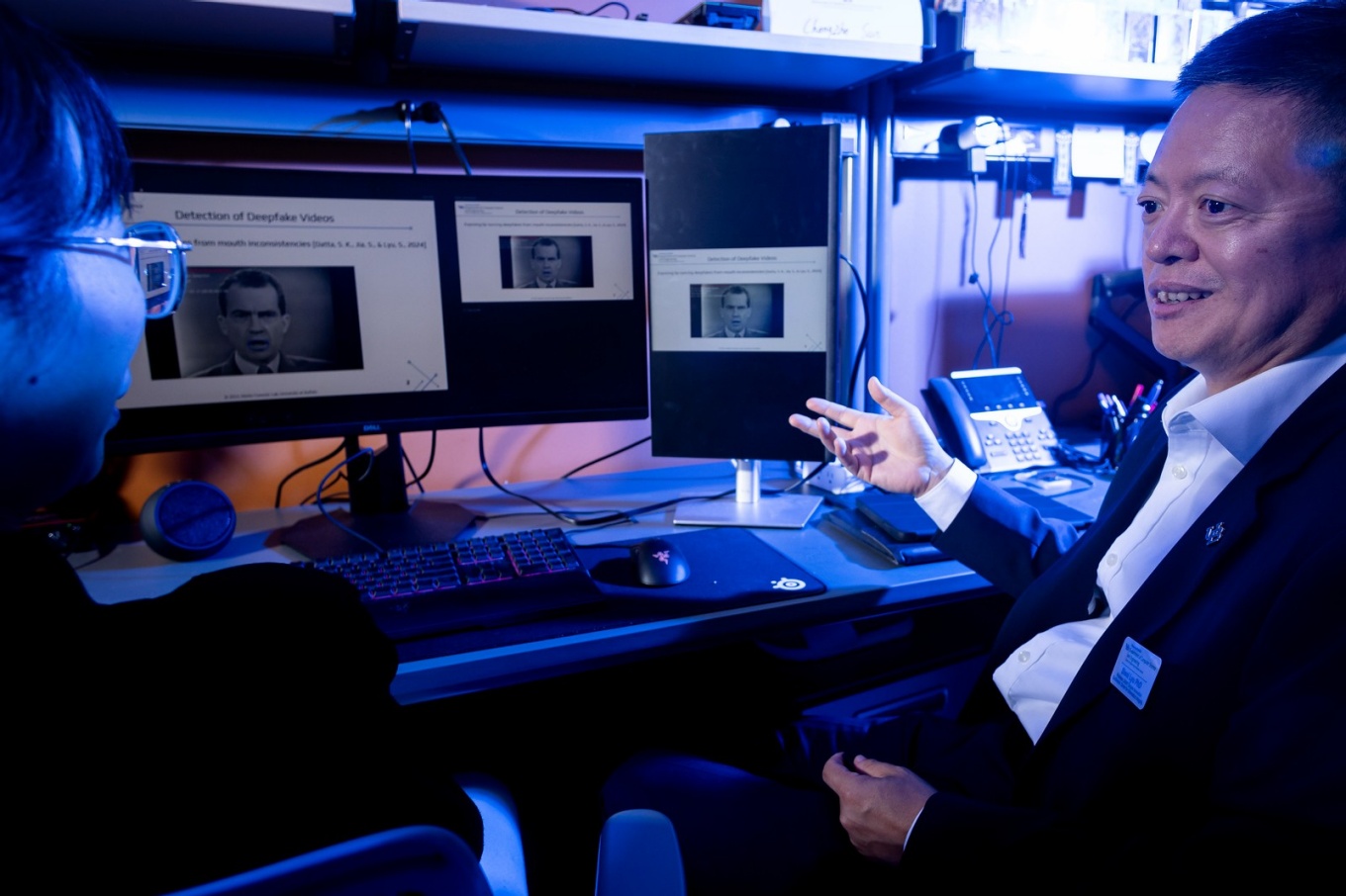 Siwei Lyu siting in front of computer screens. 
