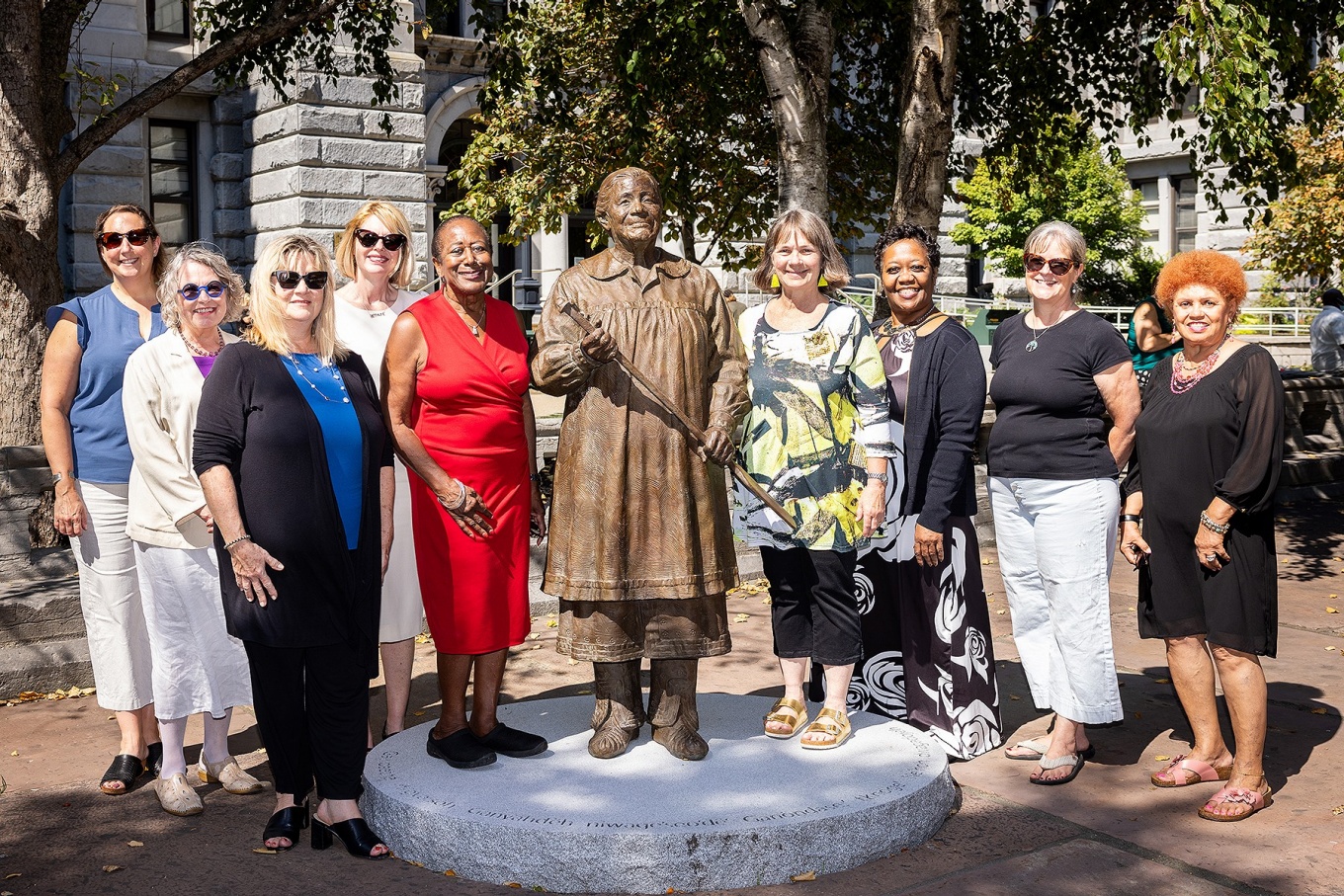 A group of women posing with a statue. 