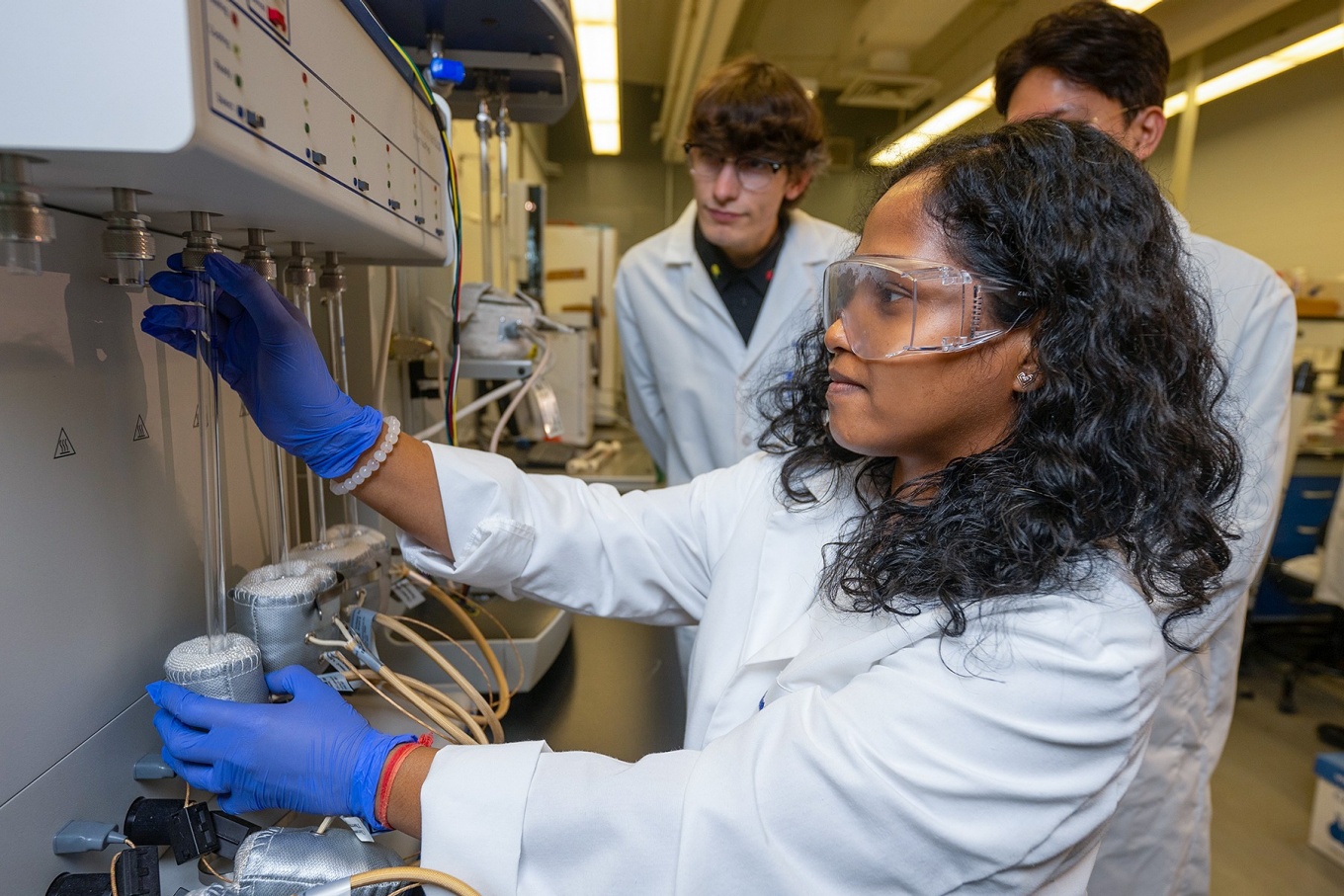 Three students in Miao Yu's lab work equipment to test the metal membranes they're working on. 