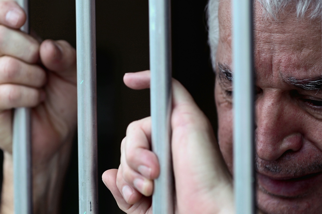 A distraught person behind bars. 