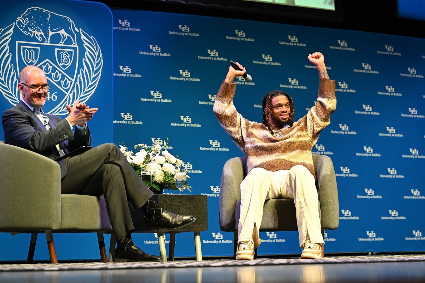 Damar Hamlin raises his arms triumphantly during his Distinguished Speakers Series appearance. 
