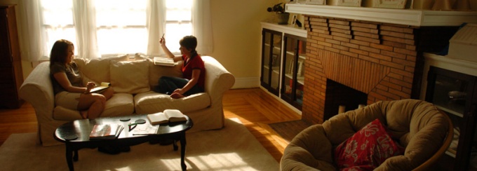 Two female students sit on the couch studying in the living room of a typical Buffalo apartment. 