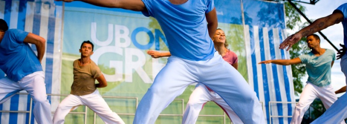 Two male dancers in blue gesture on stage at a UB on the Green outdoor event. 