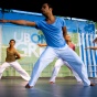 Two male dancers in blue gesture on stage at a UB on the Green outdoor event. 