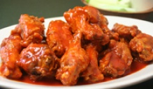 Photo of a plate of saucy chicken wings. 