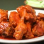 Photo of a plate of saucy chicken wings. 